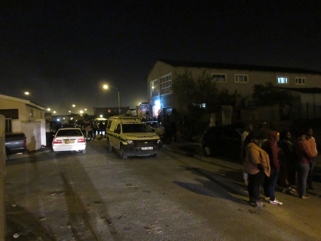 Schaulustige bei einer Schießerei neben einer Taverne in einem Township